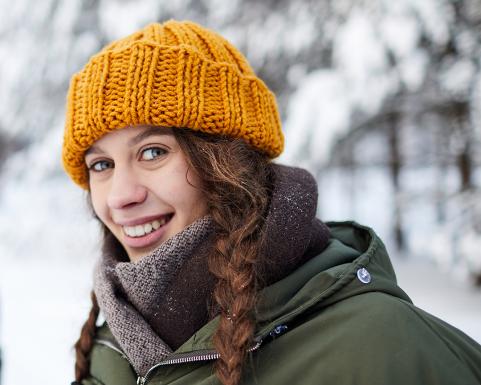 Ulkoileva nainen katsoo hymyillen kohti.
