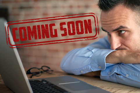 Coming soon. Mies tuijottaa läppärin ruutua ja odottaa.