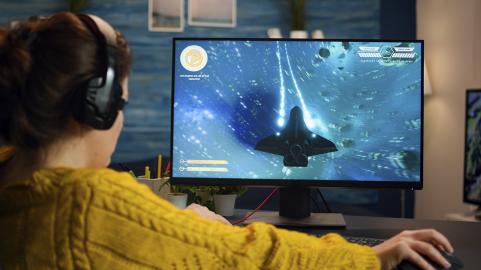 Nuori pelaa videopeliä keltainen villapaita päällä.